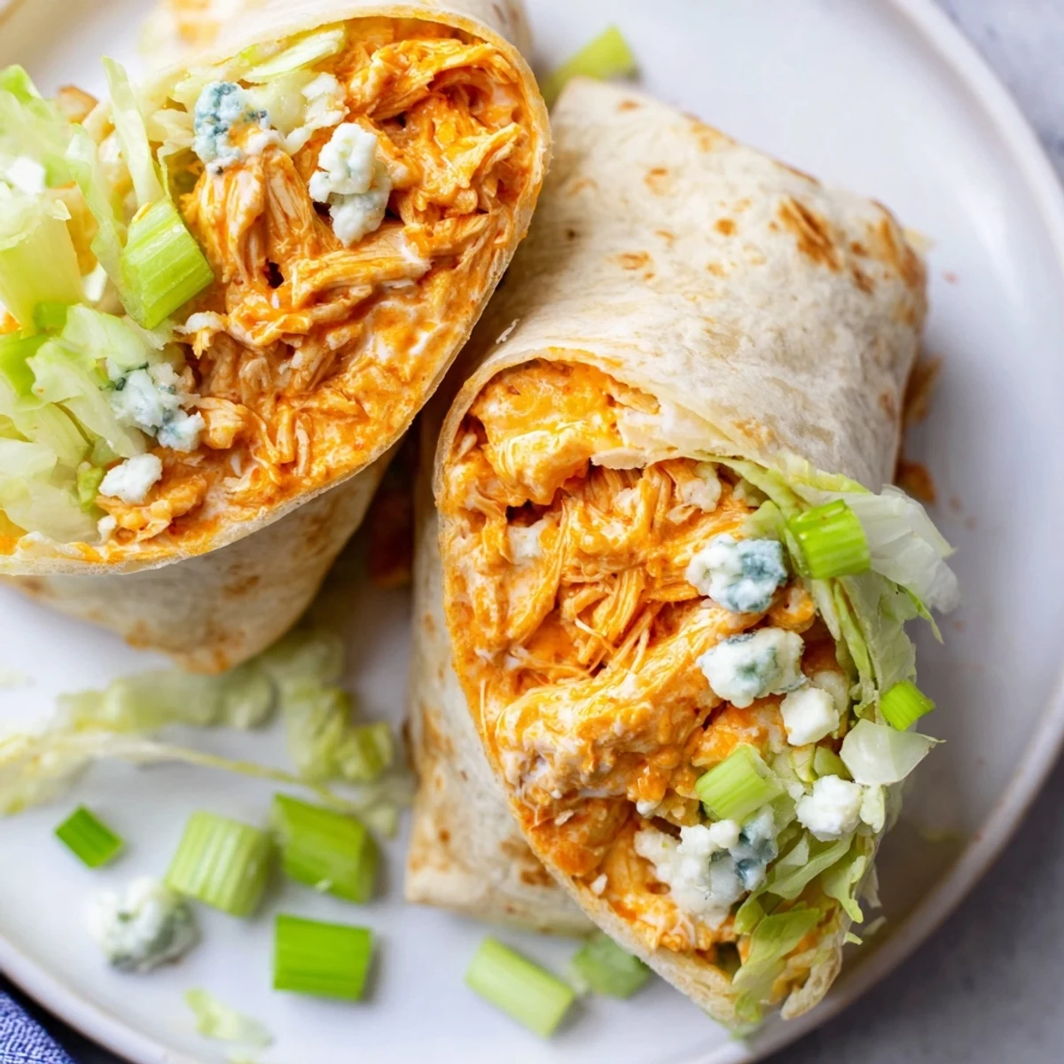 Buffalo chicken dip wrap sliced in half, revealing creamy, cheesy filling and fresh lettuce.