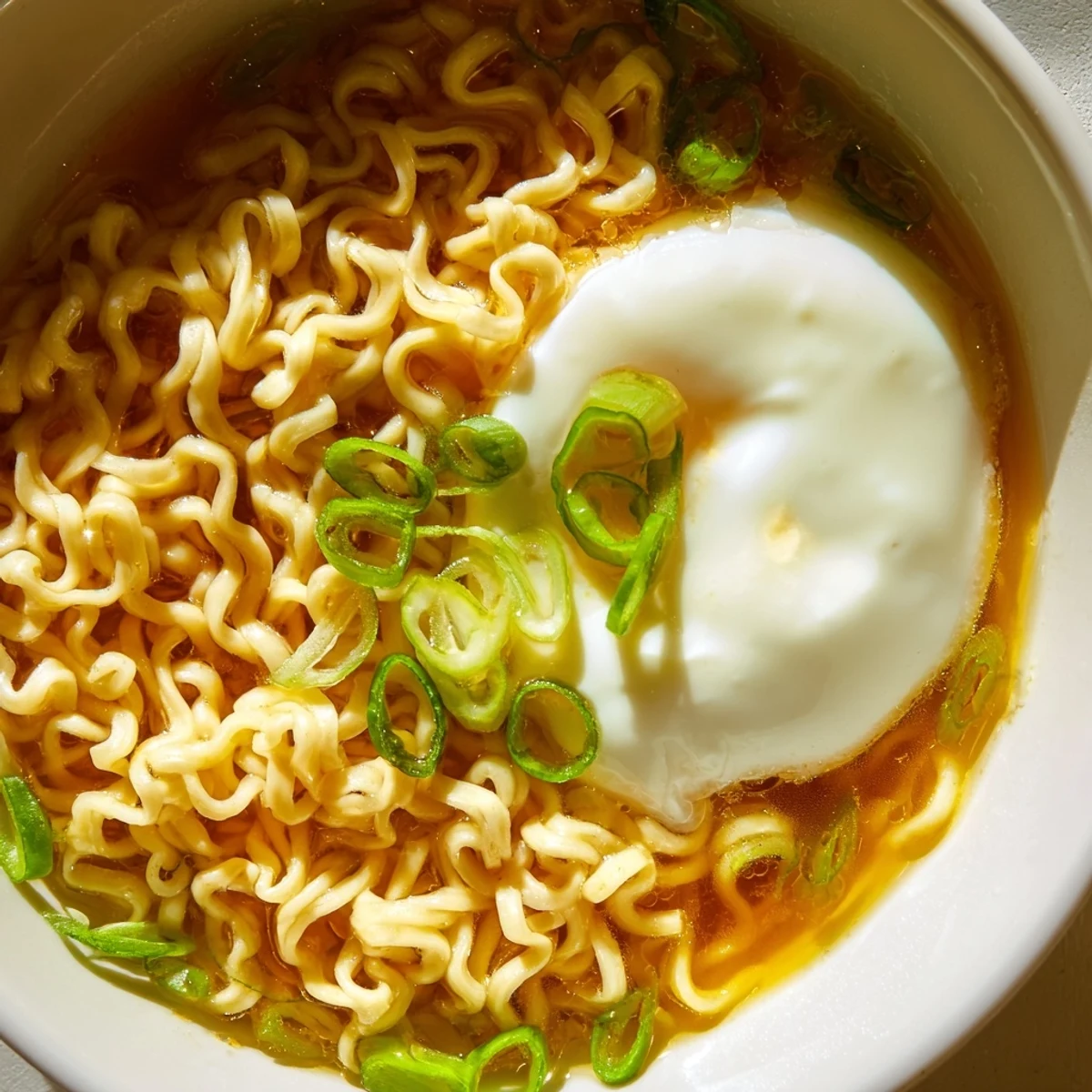 Steaming bowl of upgraded instant ramen with a perfectly cooked soft-boiled egg and green onions.