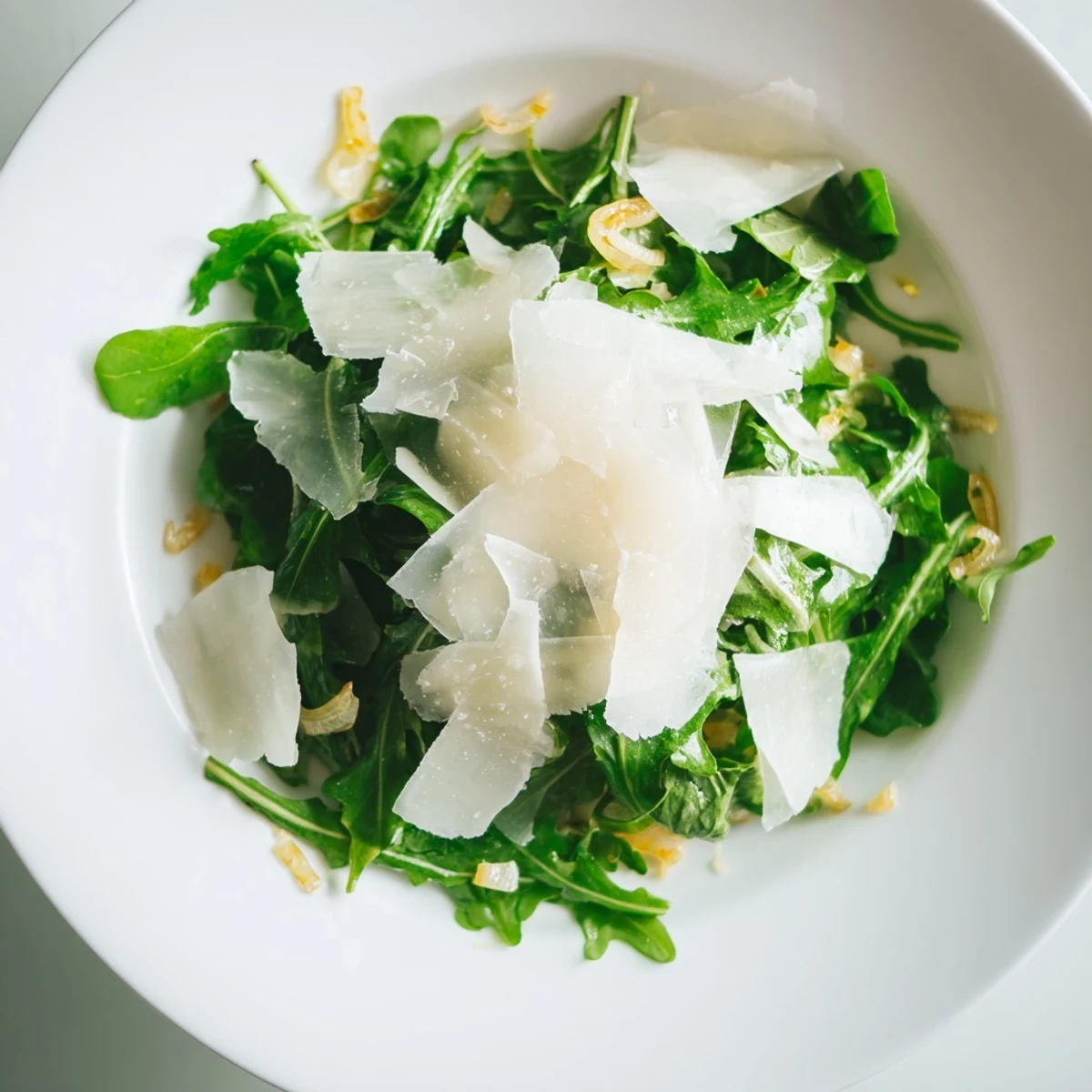 Fresh arugula salad with a tangy lemon dressing, topped with shaved Parmesan for delicious flavor.