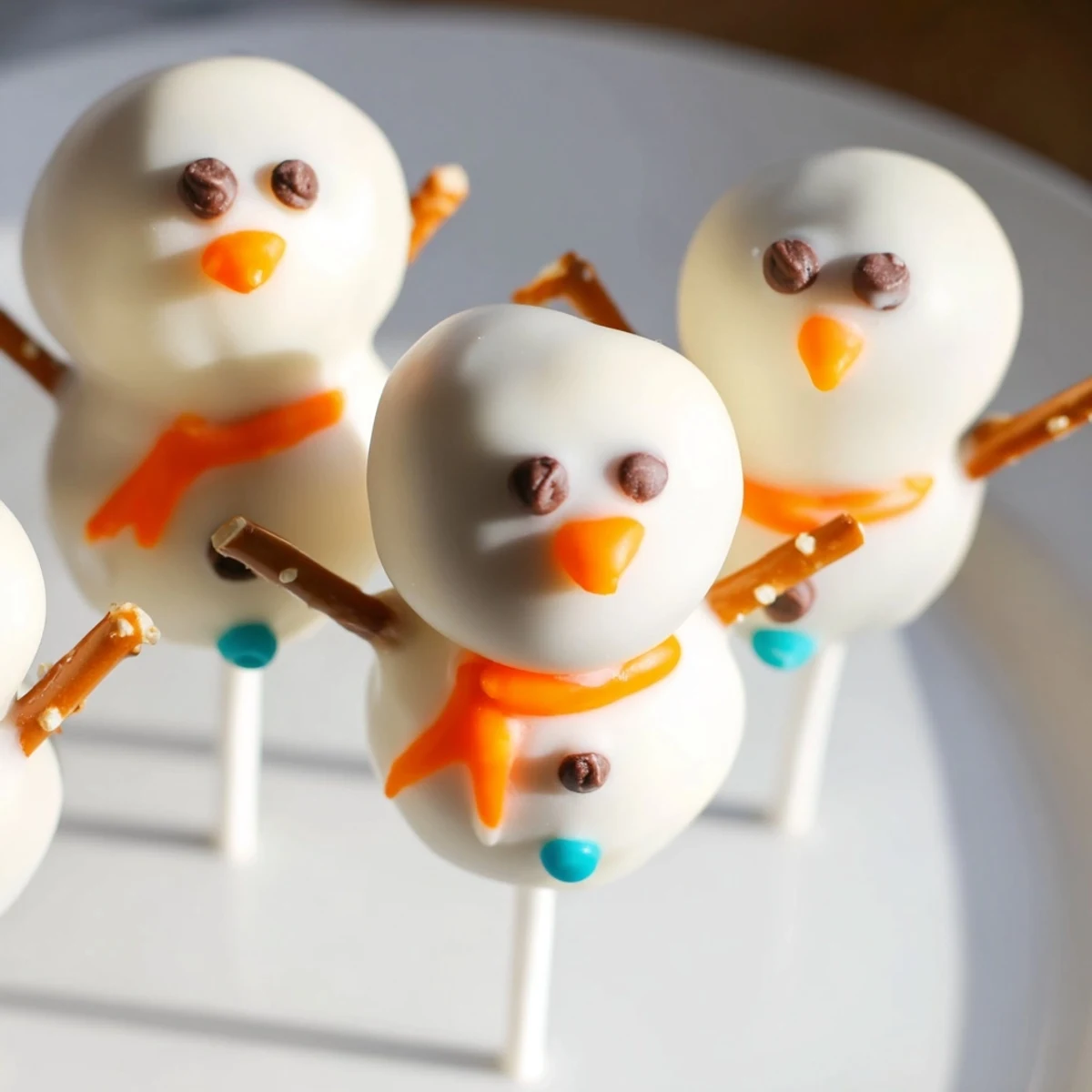 Perfectly round Oreo Snowman Cake Pops, decorated with chocolate chips, ready to bring holiday cheer.