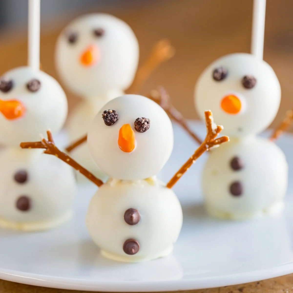 White chocolate-covered Oreo Snowman Cake Pops, a delicious, festive dessert for your winter celebration.