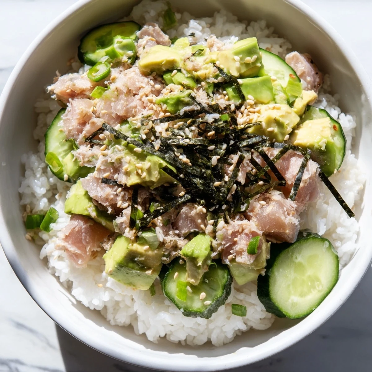 Creamy avocado, flaky tuna, and crisp cucumber sit atop warm jasmine rice in this vibrant Tuna Avocado Rice Bowl.