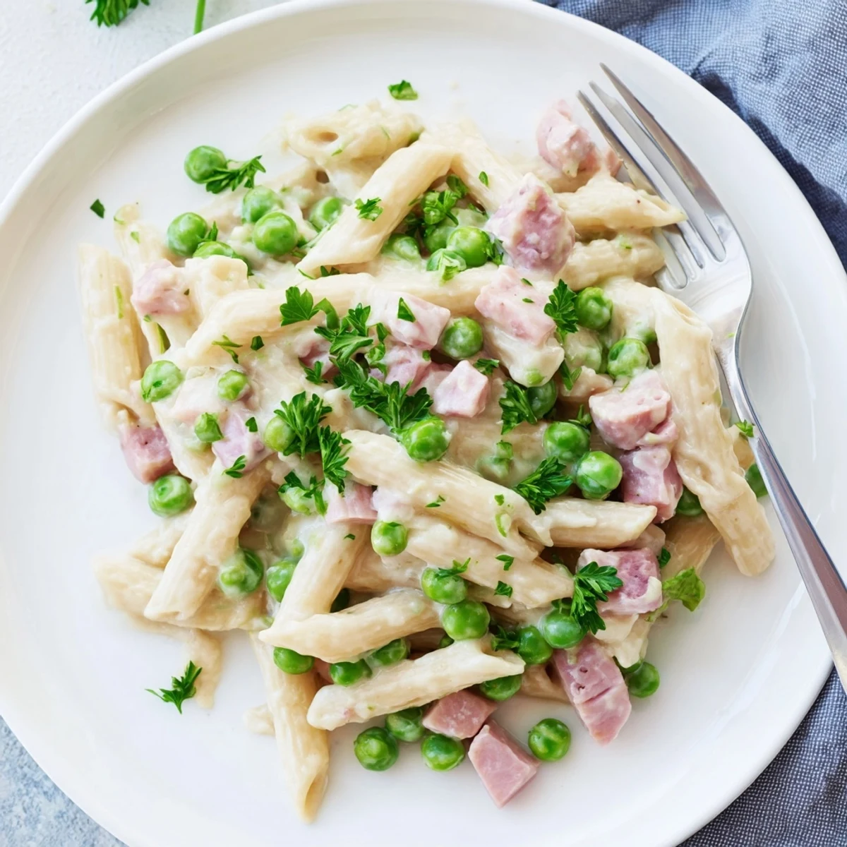 A close-up of creamy Spring Pea & Ham Pasta with penne coated in a rich sauce, bright green peas, and diced ham.
