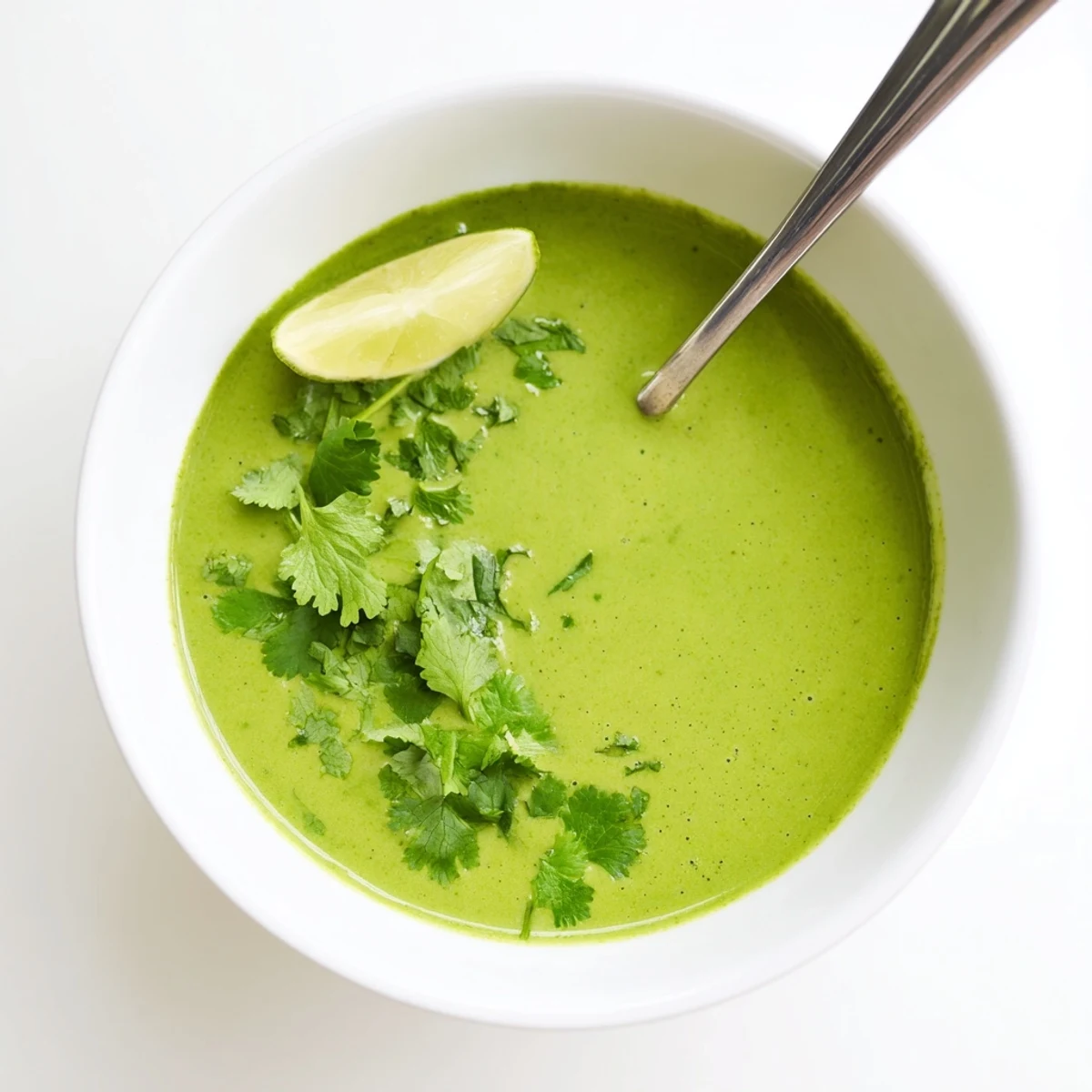 A ladle serving vibrant Spinach Coriander Lemongrass Soup, showcasing its creamy coconut milk texture and fresh green herbs.