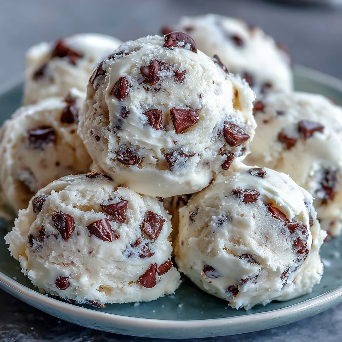 A scoop of Greek Yogurt Cookie Dough with mini chocolate chips on a chilled glass plate.