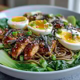 Healthy Miso Chicken Noodle Bowls topped with halved soft-boiled eggs, sesame seeds, and scallions, with a side of chili oil for added heat.