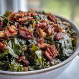 A steaming bowl of soul food collard greens with tender smoked turkey and onions, a Southern classic bursting with smoky flavor.