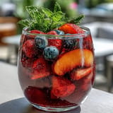 Refreshing peach and berry Summer Sangria Mocktail poured over ice, ready for sipping.