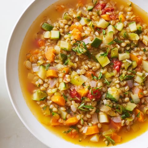 A warm bowl of Simple Homemade Grain and Vegetable Soup, garnished with fresh parsley and lemon.