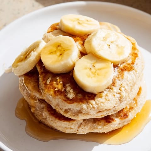 Fluffy Weekend-Brunch Banana Pancakes featuring sliced bananas and golden edges, ready for a delicious breakfast.