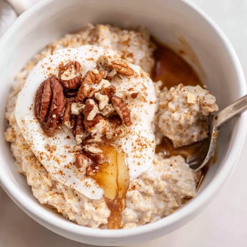 Warm, spiced Pumpkin Spice Latte Oats, a comforting breakfast with a swirl of maple syrup topping.