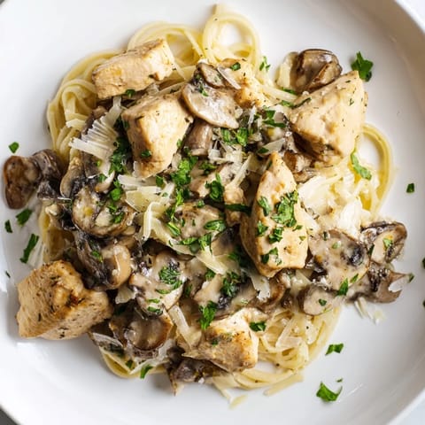 A close-up of creamy mushroom chicken pasta shows the glistening sauce coating each pasta strand.