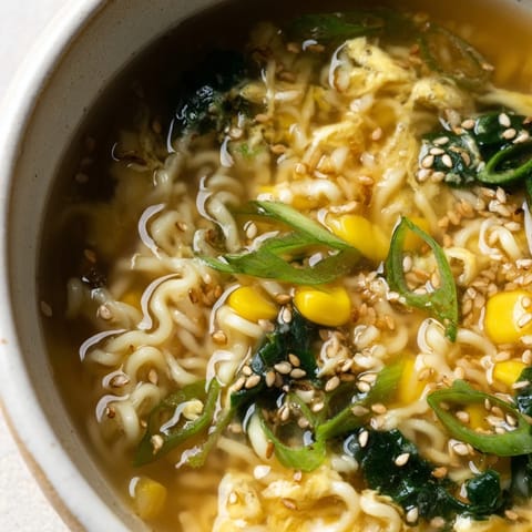 A comforting bowl of Elevated Ramen Egg Drop Soup served hot with corn, spinach, and sesame seeds for extra flavor.  