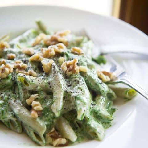 Hearty Creamy Spinach Walnut Pasta twirled on a fork, showing the velvety vibrant green sauce.