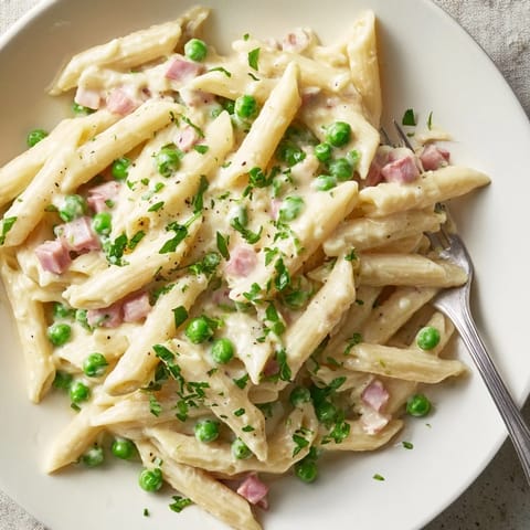 Spring Pea & Ham Pasta served in a white bowl, garnished with fresh parsley and grated Parmesan, perfect for a comforting family dinner.