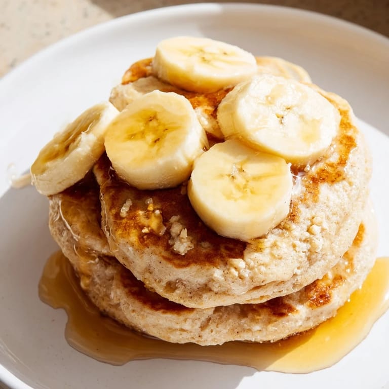 Fluffy Weekend-Brunch Banana Pancakes featuring sliced bananas and golden edges, ready for a delicious breakfast.