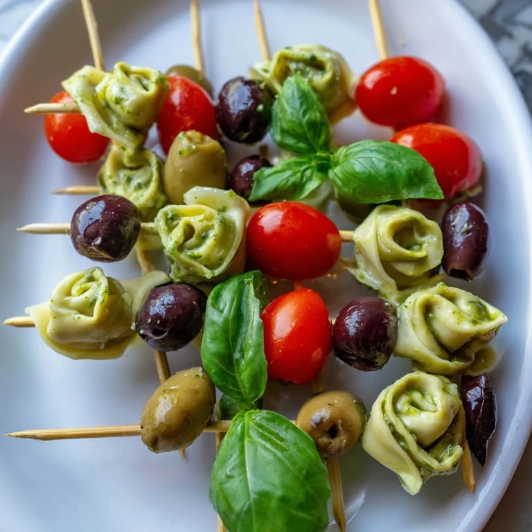 Freshly assembled Appetizer Skewers, boasting a medley of tortellini, basil, olives, and vibrant pesto arranged beautifully.