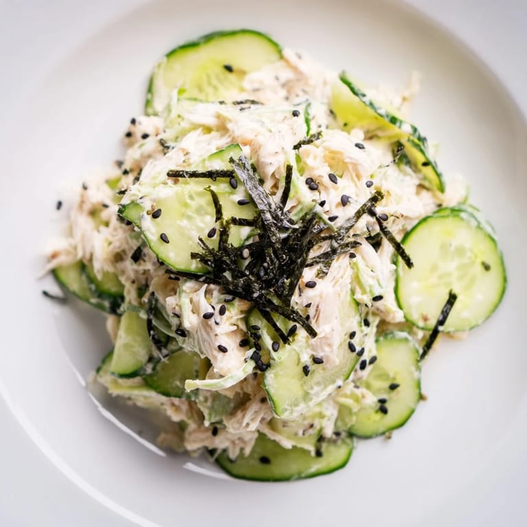 California Roll Cucumber Salad served chilled with pickled ginger on a white plate.