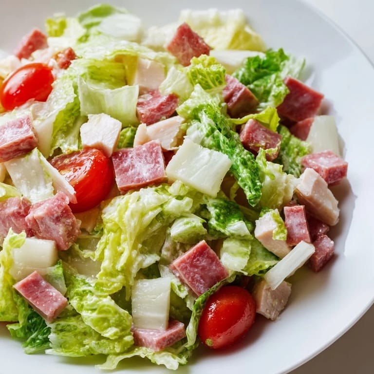 Close-up of Italian Deli Chopped Chicken Salad showing juicy chicken, spicy salami, crunchy vegetables, and melted provolone in a rustic bowl.