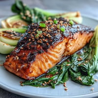 Miso Glazed Salmon with Sesame Bok Choy, glistening and caramelized, served with vibrant greens.